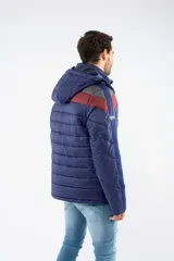 Campera puffer de nylon con relleno de guata, diseño capitoneado y capucha desmontable. Presenta un patrón de chevron en color azul sobre base negra, cierre frontal y bolsillos laterales con cierre.
