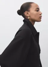 Chaqueta corta de corte recto con cuello camisero, cierre frontal de botones y dos bolsillos de parche laterales. Presenta mangas largas y forro interior.