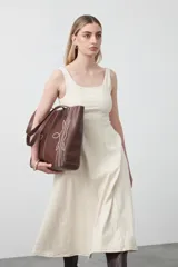 Vestido midi sin mangas de color azul oscuro, con escote cuadrado y silueta evasé. Presenta costuras a contratono en color blanco que recorren verticalmente el diseño, aportando estructura y un detalle gráfico. Confeccionado en tejido con cuerpo y caída firme.