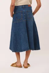 Falda midi de jean azul oscuro, con corte ligeramente acampanado y detalle de costura central vertical. Presenta paneles horizontales a la altura de la cadera que simulan bolsillos.