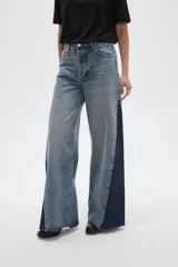 Pantalon de jean de corte ancho con diseño color block, combinando paneles de denim lavado claro en el centro y denim azul oscuro en los laterales. Presenta tiro medio y terminaciones deshilachadas en el ruedo.