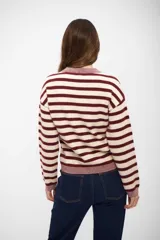 Buzo de tejido de punto con diseño a rayas horizontales en color bordó y beige, de cuello redondo, manga larga y puños y ruedo acanalados.