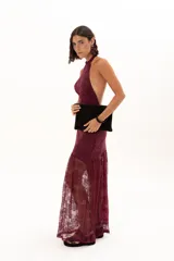 Vestido largo de encaje color bordó, con escote halter y diseño ajustado en el torso que se extiende hasta la cintura, donde continúa con una falda larga de encaje transparente.