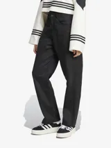 Pantalón utilitario negro de corte holgado y tejido de sarga suave, con múltiples bolsillos y tres rayas verticales en los laterales.