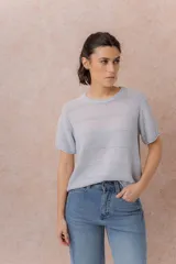 Sweater tejido celeste de manga corta con textura y delicadas líneas horizontales en relieve. Presenta cuello redondo y calce amplio con hombros caídos.