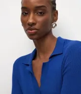 Blusa de manga larga con textura acanalada, cuello polo y escote en V. Confeccionada en tejido de viscosa y poliamida, presenta un corte regular que se ajusta de forma anatómica al cuerpo.