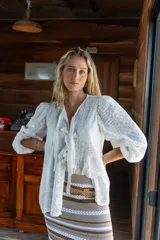 Camisa blanca de broderie con escote en V y lazos frontales para anudar. Presenta mangas globo 3/4 con puños elásticos y un diseño holgado.