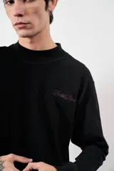 Remera negra de manga larga con cuello alto y logo bordado en el pecho.