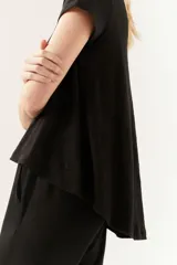 Remera negra de manga corta con cuello redondo y corte amplio, con ruedo asimétrico y más largo en la espalda.