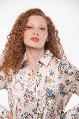 Camisa de manga larga con estampado de flores azules sobre fondo color crema, con cuello clásico y cierre frontal con botones.