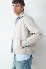 Campera de estilo casual con cuello tipo solapa, cierre frontal de cremallera y bolsillos laterales. Presenta puños y ruedo elásticos, con un acabado de textura ligera.
