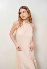 Vestido largo beige con cuello halter y detalle de broderie calado en el dobladillo inferior.