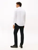 Camisa de manga larga Tommy Hilfiger confeccionada en tejido interlock, con corte slim, cuello clásico y cierre frontal de botones. Presenta el logo de la marca bordado en el pecho.