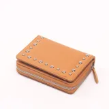 Billetera marrón de cuero sintético con cierre de cremallera y detalle de tachas plateadas.