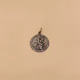 Medalla redonda de plata 925 con la imagen en relieve de San Cristóbal cargando al niño Jesús. El borde de la medalla está decorado con un diseño de cuerda trenzada.