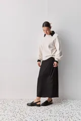 Sweater negro de tejido suave con escote redondo, mangas largas y calce relajado, con terminaciones acanaladas en cuello, puños y ruedo.