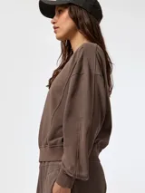 Buzo oversize marrón con cuello redondo, detalles de costuras visibles y puños y cintura de rib elástico.