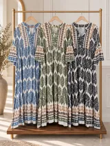 Maxi vestido largo de fibrana en color blanco con estampado paisley y geométrico en tonos azules y tostados, con escote en V, mangas largas amplias y diseño holgado con volados en la falda.