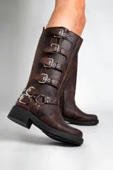 Borcegos negros de caña alta confeccionados en cuero sintético, con hebillas plateadas en los costados y cierre lateral. La altura de la caña es de 33,5 cm y la base mide 5 cm.