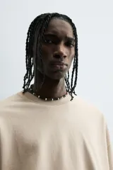 Camiseta color caqui de corte holgado, con cuello redondo y mangas cortas. Acabado con efecto lavado y ruedo irregular.