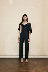 Mono de sastrería negro sin tirantes, con accesorio de satén y algodón que se puede atar a la cadera o usar como chal. Presenta un chal de satén texturizado y un top tipo corsé con pantalones de sastrería.