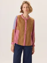 Camisa de algodón con diseño de bloques de color en tonos marrón, rosa y lila. Presenta cuello redondo, cierre frontal con botones y mangas largas.