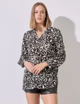 Blusa estampada en blanco y negro, marca Grand & Greene. Tiene cuello a la base, escote en V y abertura con botones. La manga es larga y amplia con detalle plisado.