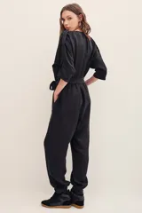 Monoprenda de cupro y viscosa color negro, de manga larga, cuello redondo con botones y bolsillos en el pecho. Presenta diseño holgado con puños elastizados en los tobillos.