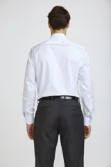 Camisa de vestir blanca de corte clásico, con cuello rígido, cierre frontal de botones y mangas largas con puños abotonados.