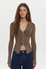 Cardigan tejido en rib con hilado de lurex, color crudo, calce al cuerpo, cuello polo, mangas largas con aberturas y cierre metálico frontal bidireccional.