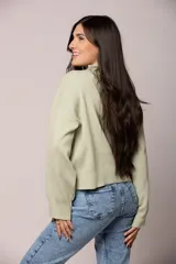 Buzo tejido de punto en color blanco crema, con cuello redondo alto y mangas largas con puños acanalados.