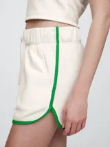 Short de piqué color crema con ribetes en color verde, cintura elástica con cordón de ajuste y diseño deportivo.