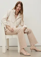 Jeans tiro medio color beige con diseño flare y bajo deshilachado, con cierre de cremallera y botón, trabillas y cinco bolsillos.