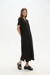 Vestido midi de corte holgado, color negro, con mangas cortas, cuello en V y detalle de cuentas decorativas en el escote.