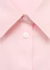 Camisa oversize color rosado, con cuello camisero, manga larga con puños abotonados, bolsillo de parche en el pecho y cierre frontal con botones ocultos.