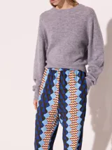 Pantalón con estampado geométrico en tonos azul, celeste, marrón y verde. Tiene cintura y tobillos elastizados con tancas para regular.