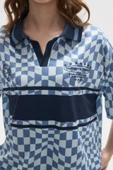 Remera tipo chomba de manga corta con cuello camisero, confeccionada en tejido con estampado de tablero ondulado en tonos rosado y blanco, con franja horizontal y detalles gráficos en color bordó.