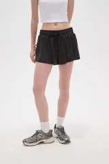 Short de poliéster color celeste, de calce holgado y tiro alto, con cintura elástica ajustable mediante cordón y bolsillos laterales.