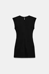 Vestido corto de estilo militar en color negro, con cuello redondo, hombreras y manga sisa. Presenta un diseño frontal con falsos botones dorados dispuestos en filas horizontales. Cierre lateral con cremallera oculta y abertura en la espalda con botón.