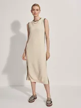 Vestido midi tejido color crema con ribete negro en cuello, sisas y ruedo. Presenta aberturas laterales en el ruedo.