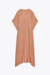 Vestido largo tipo kaftán confeccionado en lino a rayas verticales en tonos naranja y verde. Tiene cuello redondo con escote en V, mangas cortas amplias, acabado deshilachado y cinturón de cordón en el mismo tejido.