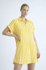 Vestido camisero de silueta relajada, con cuello clásico, cierre frontal de botones y mangas cortas con dobladillo. Presenta un estampado de cuadrícula irregular en color rojo sobre fondo blanco.