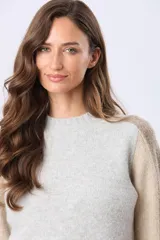 Buzo tejido de punto con cuello redondo y mangas largas. Presenta un diseño de bloques de color con franjas en tonos contrastantes a lo largo de las mangas y un detalle de etiqueta de cuero en el ruedo.