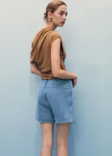 Short skort de tiro medio y diseño cruzado estilo falda pantalón, confeccionado en tejido de algodón denim vaquero con cierre de botón frontal.