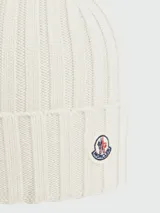 Gorro de lana tejido a punto acanalado, color bordó, con parche circular del logo de Moncler en el frente.