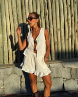 Blusa sin mangas color blanco, tejida con textura acanalada y escote pronunciado en V, sujeta en el centro con dos apliques metálicos con forma de sol.