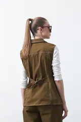 Chaleco de estilo utilitario color bordó con pespuntes blancos a contratono. Presenta solapas, cierre frontal con botones, bolsillos delanteros y un diseño estructurado.