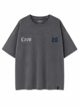 Remera de algodón con efecto lavado, color gris oscuro, de corte oversize con mangas cortas. Presenta un estampado frontal con la palabra 'Crew' en tipografía gótica y el número '26' en azul marino.