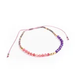 Pulsera elástica con hilo color lila, con cuentas de piedra facetadas color rosa, gris y violeta, y detalles de cuentas doradas.