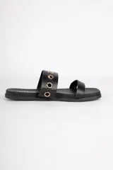 Sandalias bajas negras de símil cuero con doble tira, una de ellas con argollas metálicas doradas.
